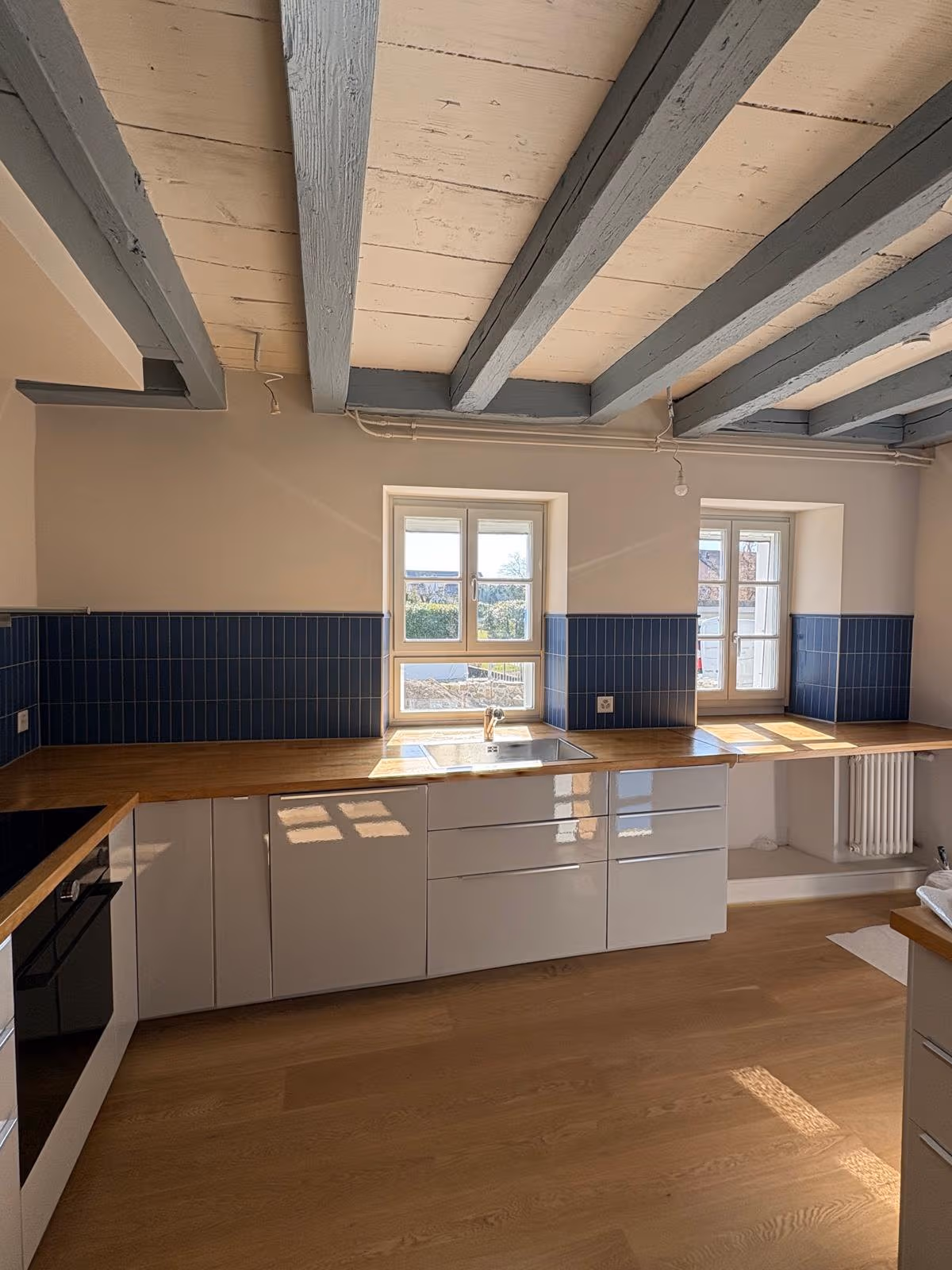 Cuisine carrelée à Nyon, crédence en faïence bleue posée à la verticale et plan de travail en bois