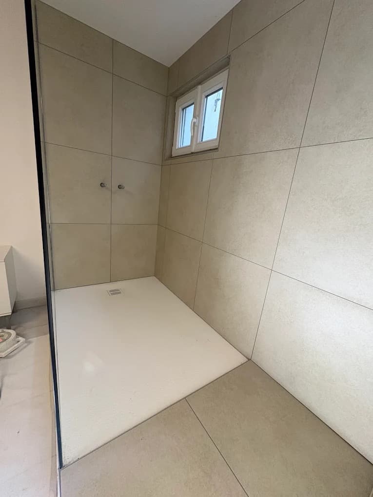 Receveur de douche extra-plat et parois carrelées beige dans une douche à l'italienne à Trélex