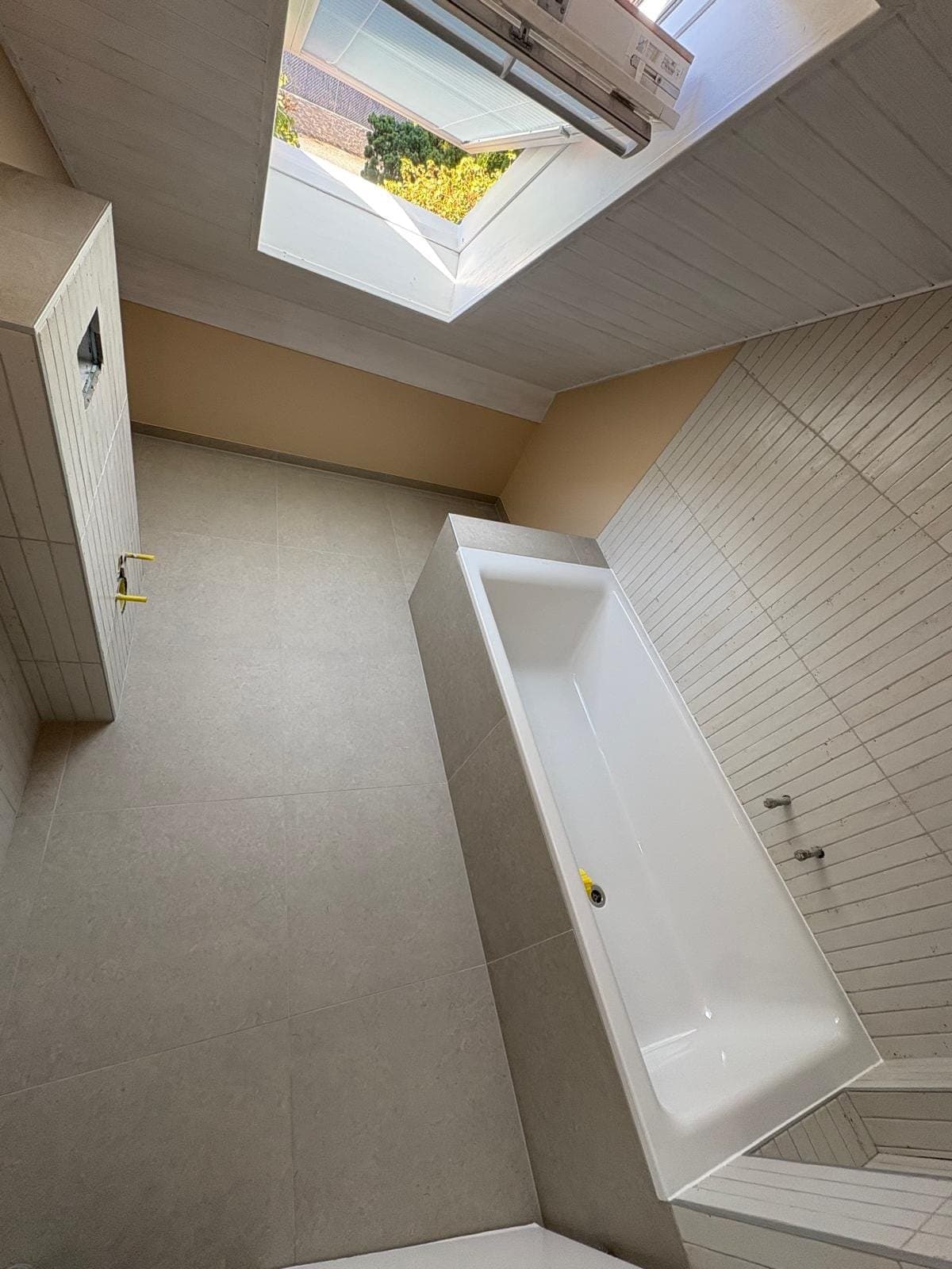 Baignoire sous une fenêtre de toit dans une salle de bain à Trélex