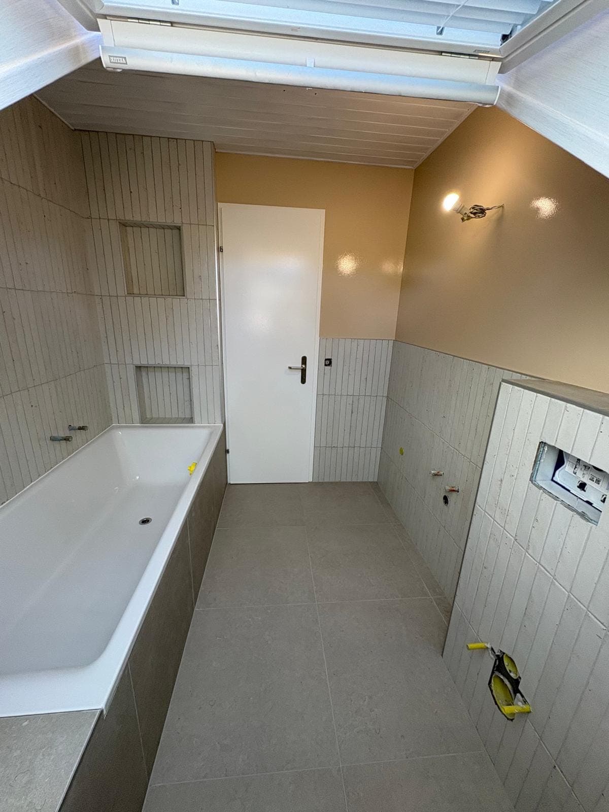 Vue d'ensemble de la salle de bain sous combles à Trélex après pose du carrelage