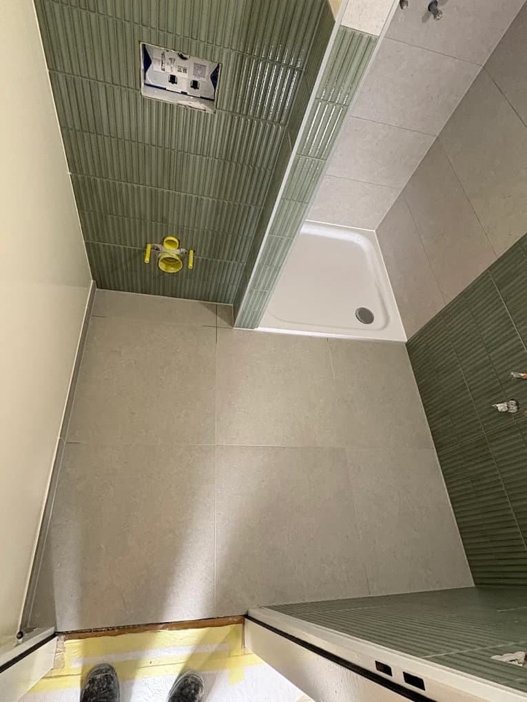 Sol carrelé et receveur dans une salle de douche à Trélex